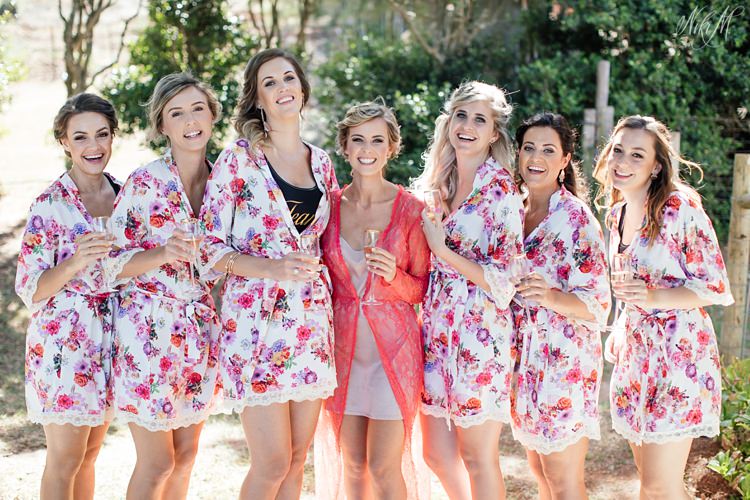 Bridesmaids laugh as they pose in their floral gowns made by Grace Infinity Dresses