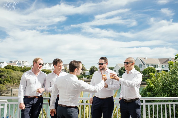Groom and groomsmen toast with whiskey in St Francis, South Africa