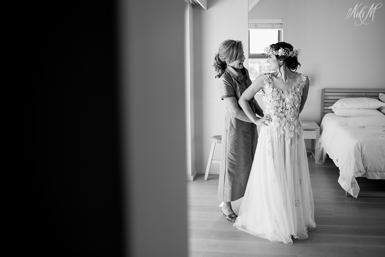 Mother of the bride helps her daughter get dressed.
