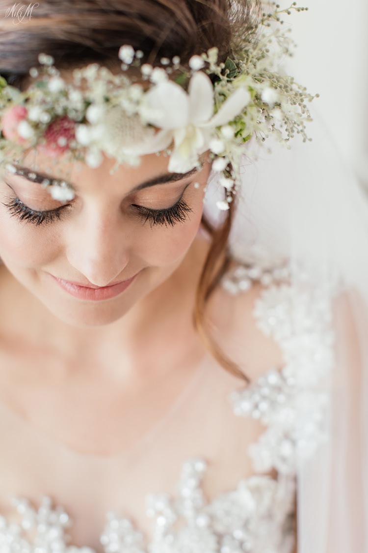 Smiling Bride looks down during her bridal portraits with an orchid flower crown