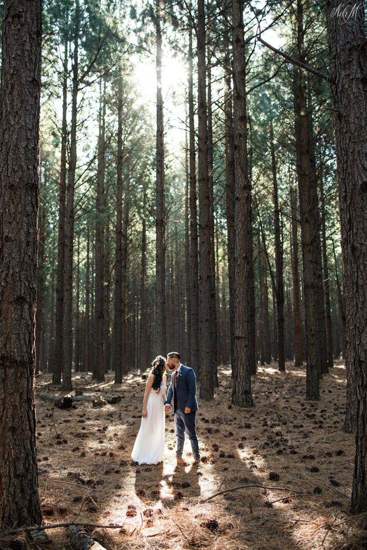 Amy and Silvino kiss amongst the tall pine trees of the forest
