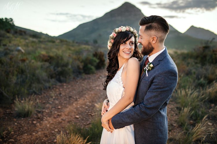 A wedding portrait of Amy and SiIvino with the Tsitsikamma mountain range behind them