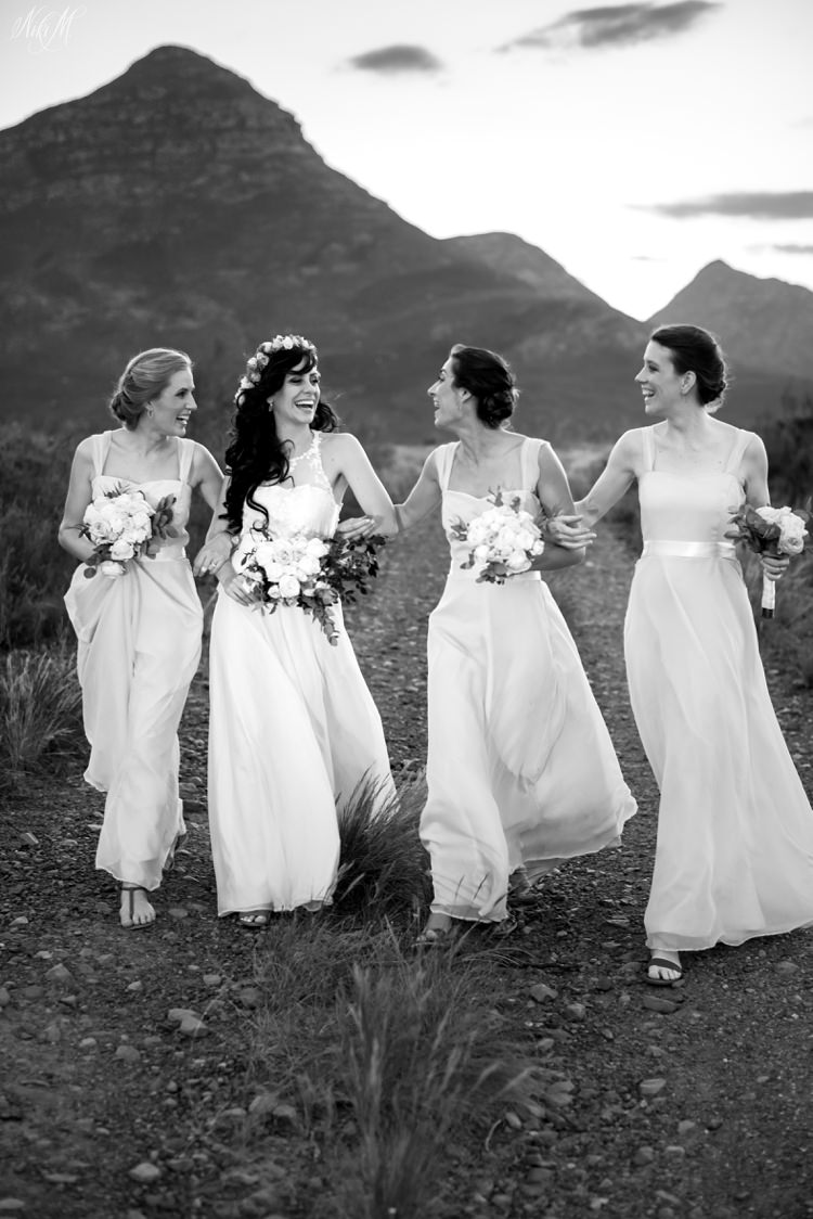 The bridesmaids walk down a mountain road