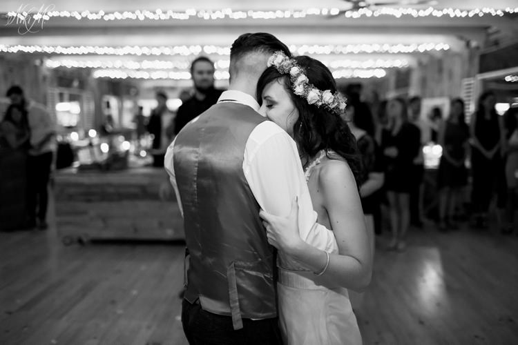 The groom and his barefoot bride grace the dance floor for their first dance under the fairy lights