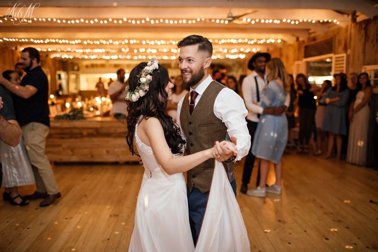 The groom and his barefoot bride grace the dance floor for their first dance under the fairy lights